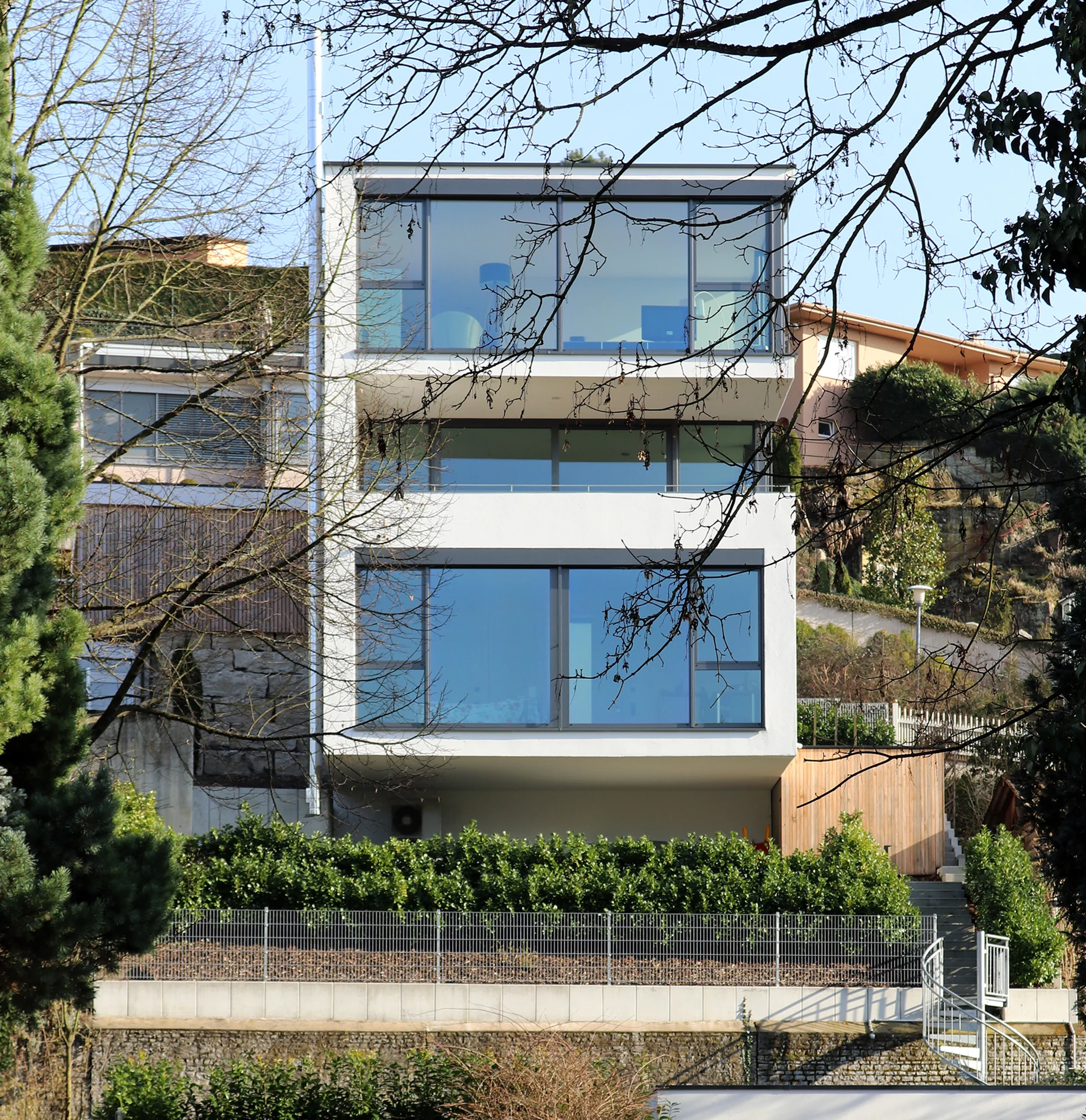 Wohnhaus Katzensteige: helle Fassade mit großzügigen Glasflächen am Hang